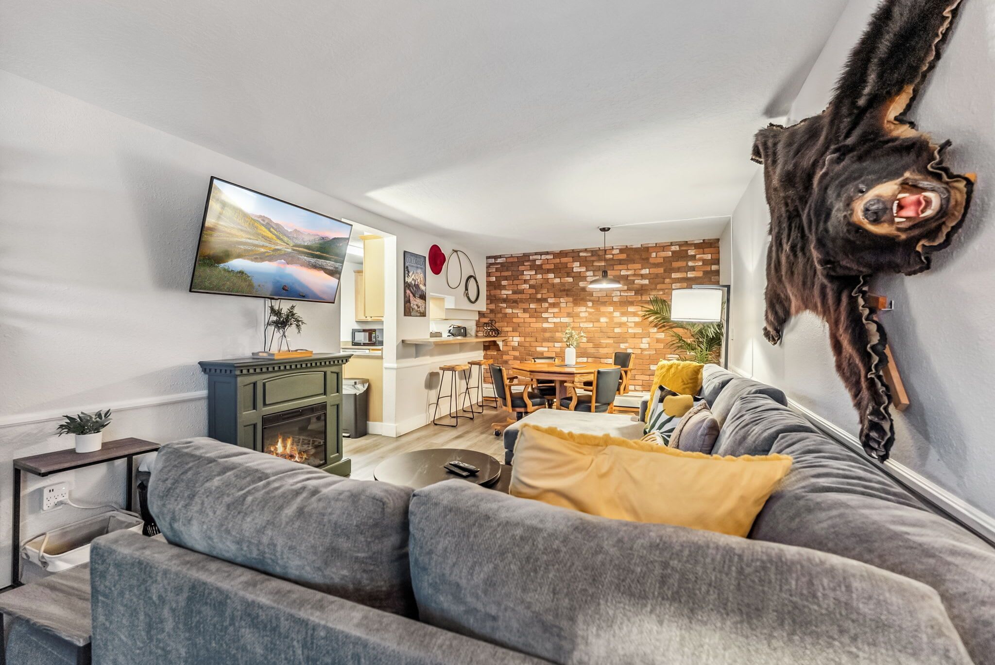A modern living room with a fireplace, a dining area, and a mounted animal head.