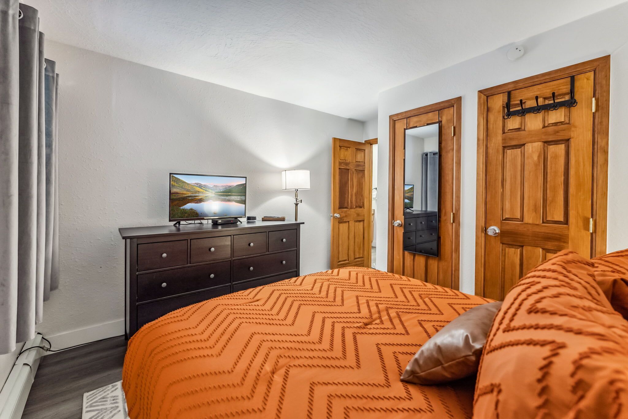 Un dormitorio con cama, cómoda, televisor y puertas de madera.