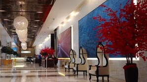Un vestíbulo de hotel con mostrador de recepción, zona de estar y un gran mural azul.