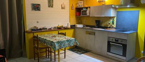 A compact kitchen with a dining table, chairs, a microwave, and a stove.