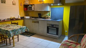 Une cuisine compacte équipée d’un four à micro-ondes, d’un four et d’un évier. On y trouve une table à manger avec des chaises et un petit tapis.