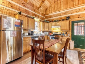 Une cuisine de style rustique, avec des meubles en bois, un réfrigérateur en acier inoxydable, une cuisinière et une table à manger avec des chaises.
