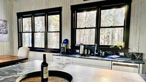 A kitchen with a marble countertop, a wine bottle, and a coffee machine.