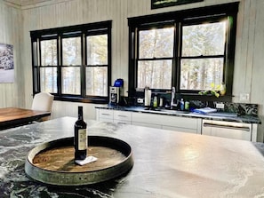 Una cocina con encimera de mármol, una botella de vino y una cafetera.