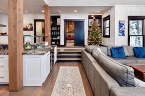 A modern living room with a sofa, a coffee table, and a Christmas tree. - Luxury Ski In / Ski Out | Hot Tub | Sleeps 10 (Whitefish)