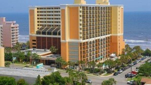 A multi-story hotel with a central courtyard, located near a beach with ocean views. - Azure Bliss. Oceanfront Condo. Sleeps 6. (Myrtle Beach)