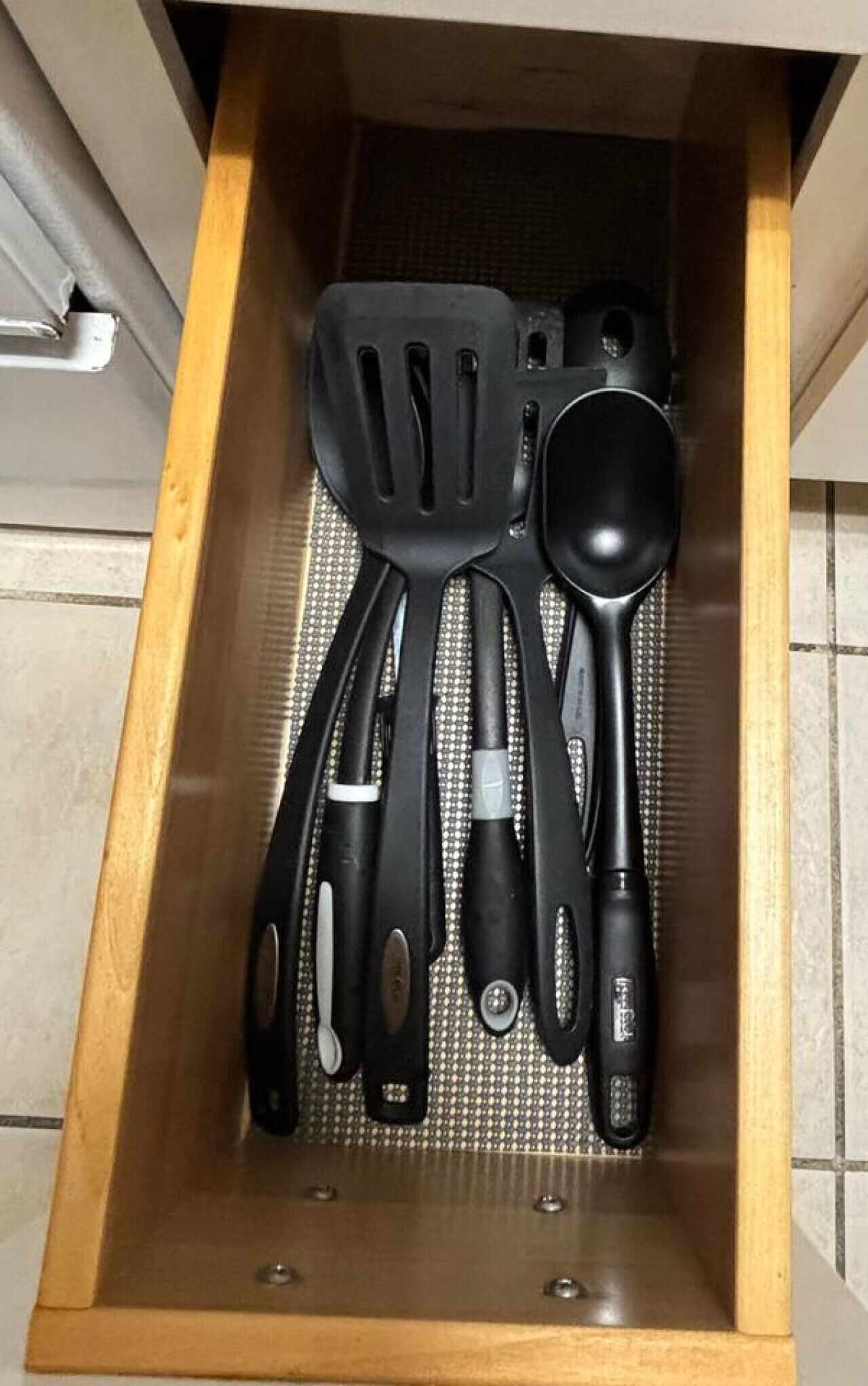 A drawer containing various kitchen utensils including a spatula, spoon, and ladle.