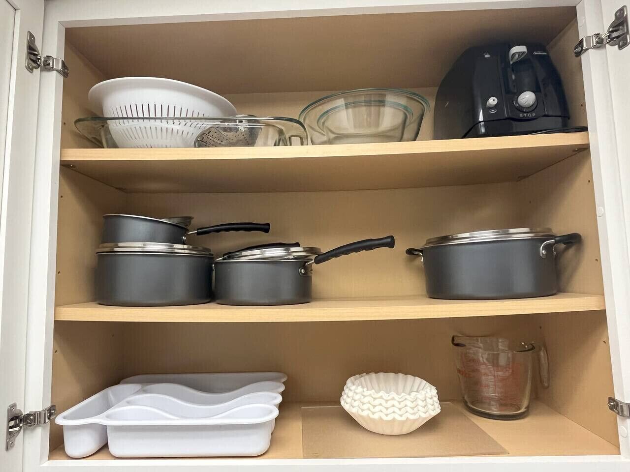 A kitchen cabinet with shelves holding various kitchenware items.