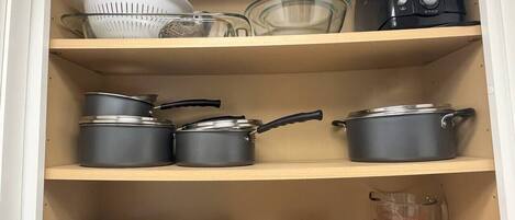 A kitchen cabinet with shelves holding various kitchenware items.