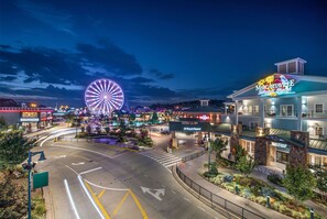 A hotel with a large Ferris wheel in the background, a well-lit street, and a landscaped area with benches.