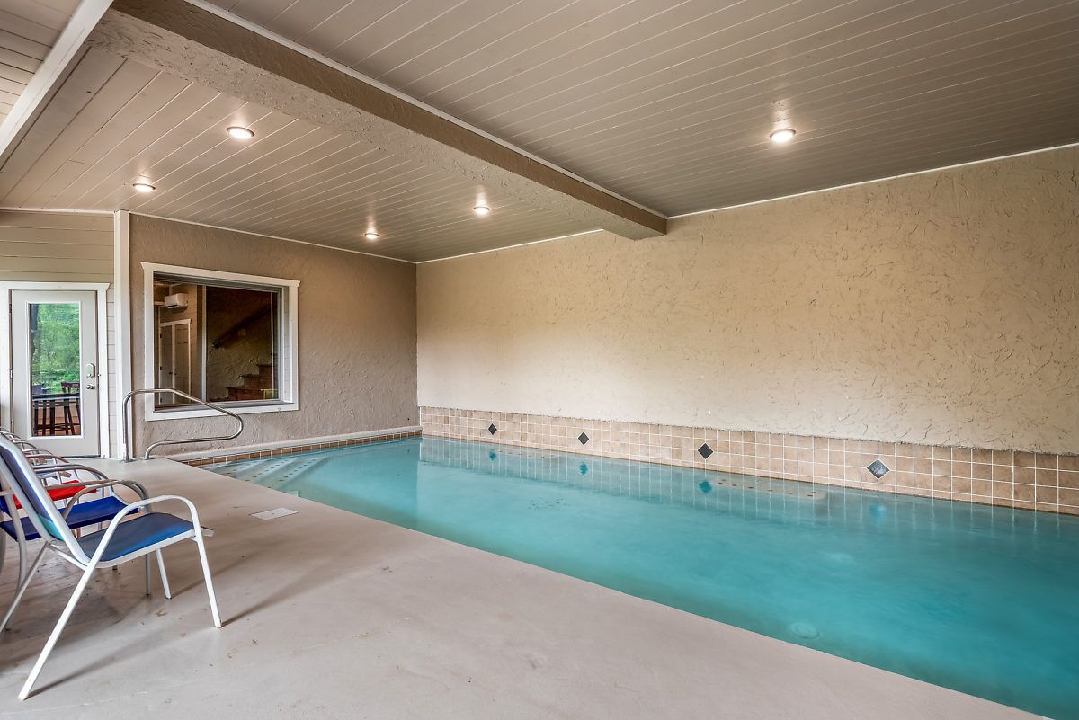 Ein Hallenbad mit klarem Wasser, einer gefliesten Wand und einer Decke mit eingelassener Beleuchtung.