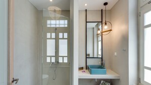 A modern bathroom with a glass-enclosed shower, a blue sink, and a mirror with a pendant light. - 1924 suites  Terrace (Chania)