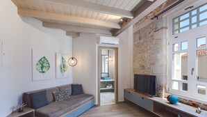 A modern living room with a built-in sofa, a TV, and artwork on the walls. - 1924 suites  Terrace (Chania)