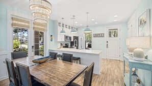 A modern kitchen with a wooden dining table, pendant lights, and a view of the outdoors.