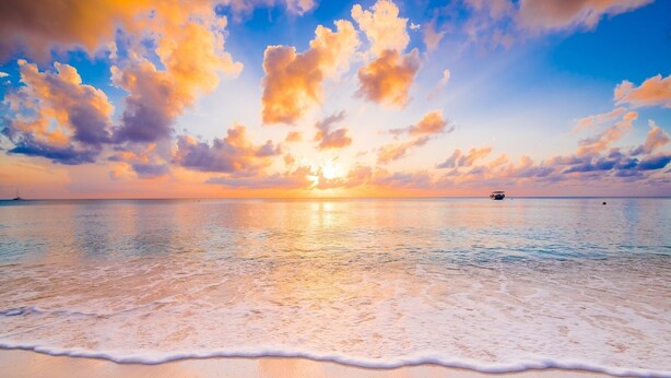 A beach with calm waters and a sunset.