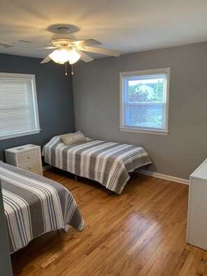 Cozy retreat with two single beds, a nightstand, and a ceiling fan.