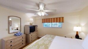 Cozy retreat with a single bed, dresser, TV, and ceiling fan, perfect for a relaxing stay.