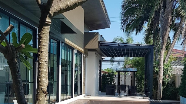 A modern house with a swimming pool, a patio with outdoor furniture, and a palm tree.