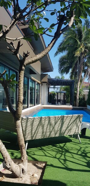 A modern house with a swimming pool, a patio with outdoor furniture, and a palm tree. - BanAmphur Pool Villa... Place for chilling out! (Chonburi)
