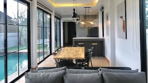 A modern kitchen with a dining area, large windows, and a pool view.