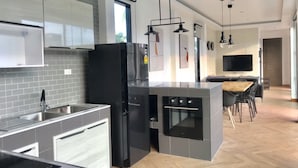 A modern kitchen with a central island, built-in appliances, and a dining area with a TV.