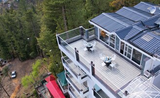 Un edificio de varios pisos con terraza en la azotea, con mobiliario exterior y una antena parabólica.