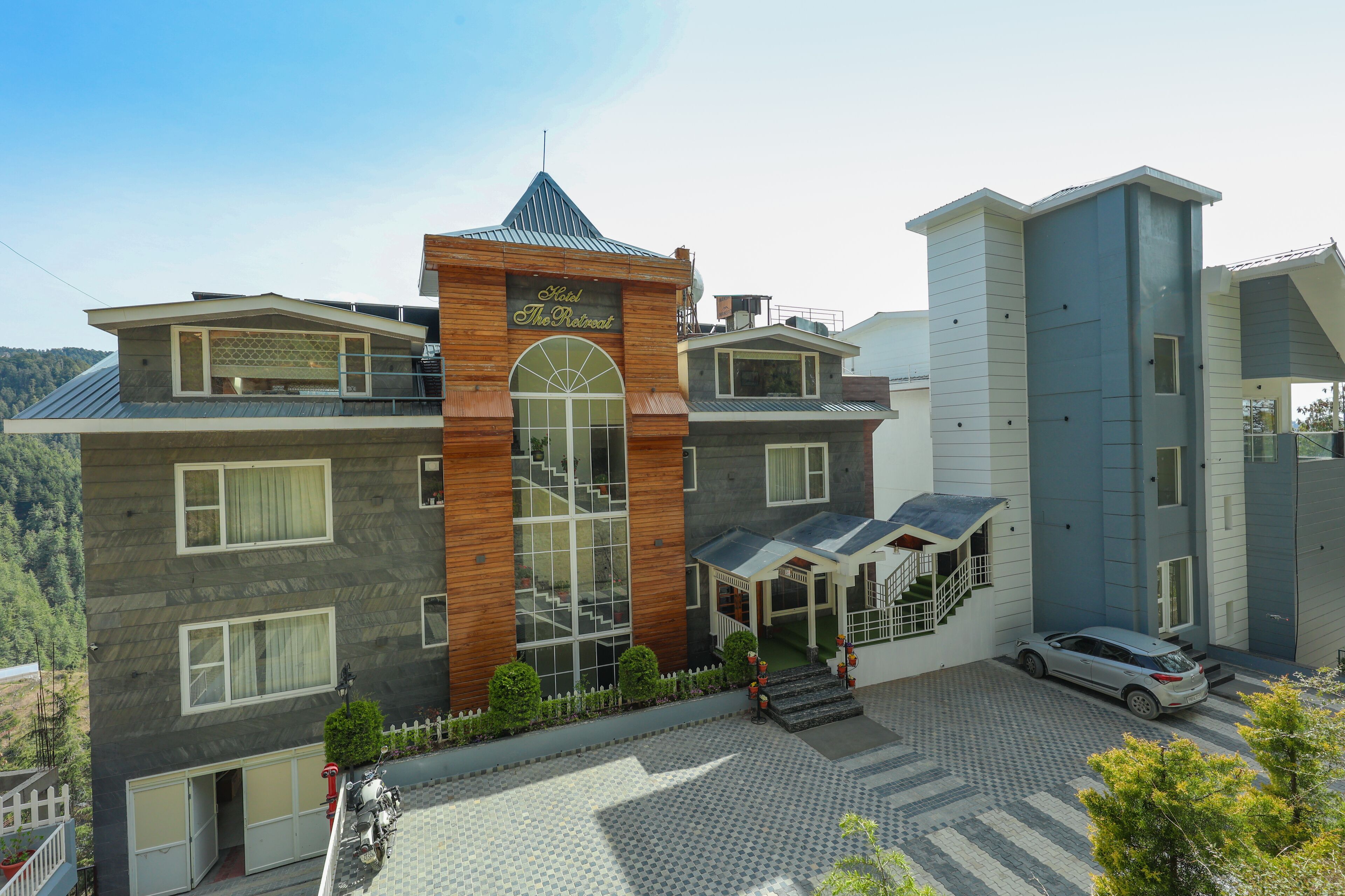 A hotel with a prominent tower, a covered entrance, and a car parked in front.