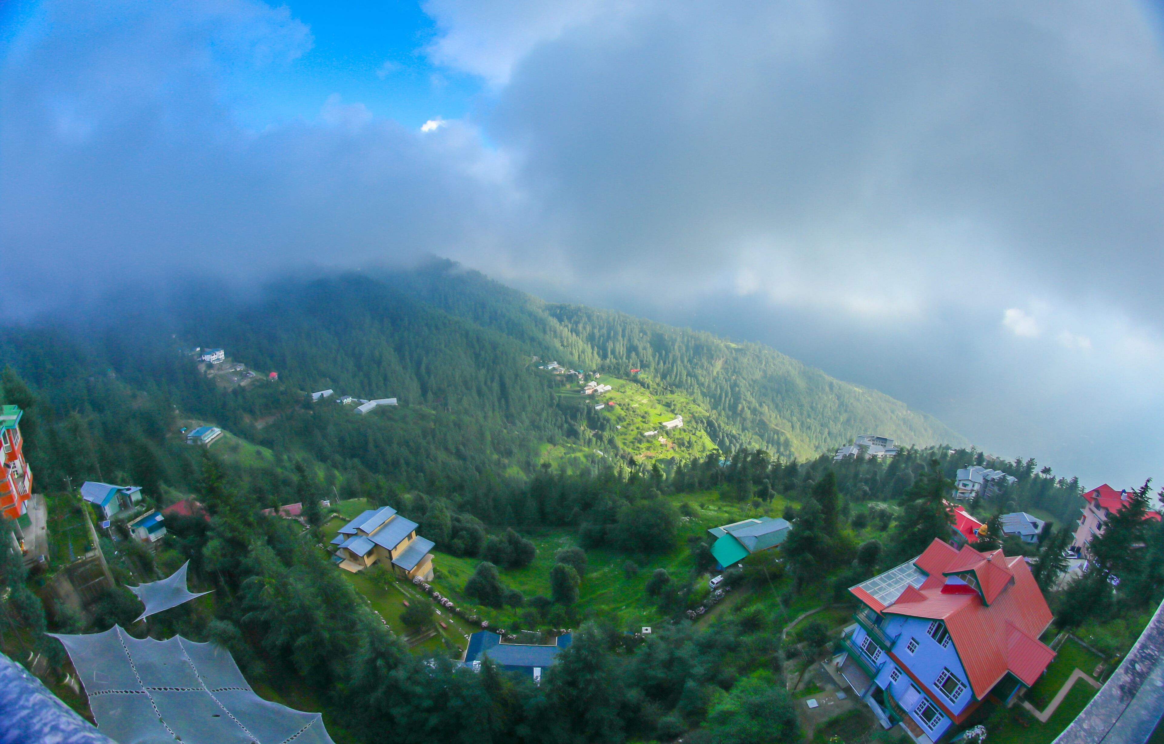 A panoramic view of a mountainous area with scattered houses and a road.