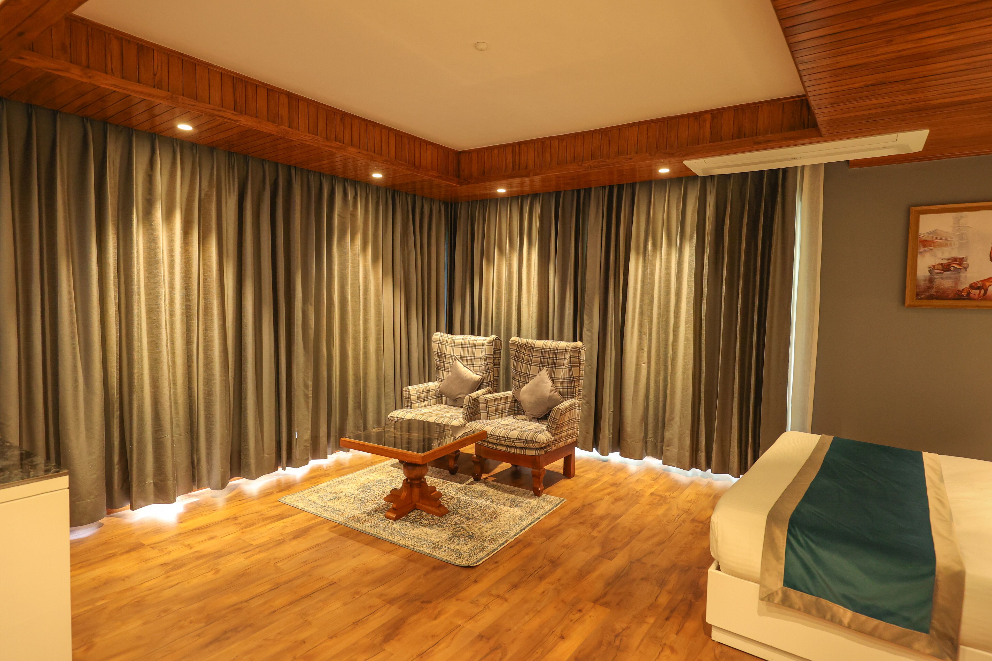 A room with wooden paneling, a plaid armchair, a white sofa, and a large window with curtains.