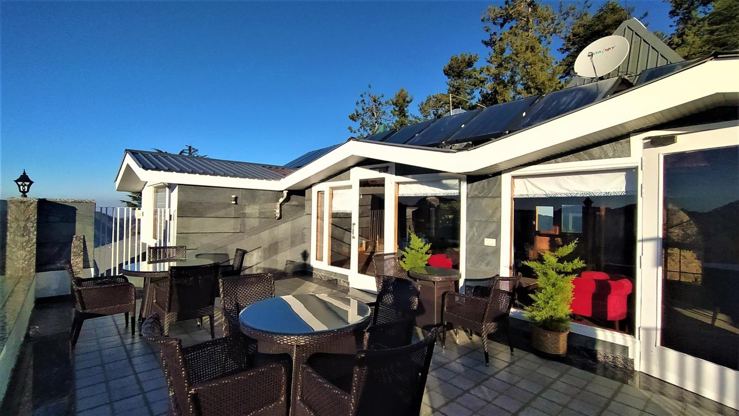 En moderne udendørs terrasse med spiseplads, solpaneler og en parabol.