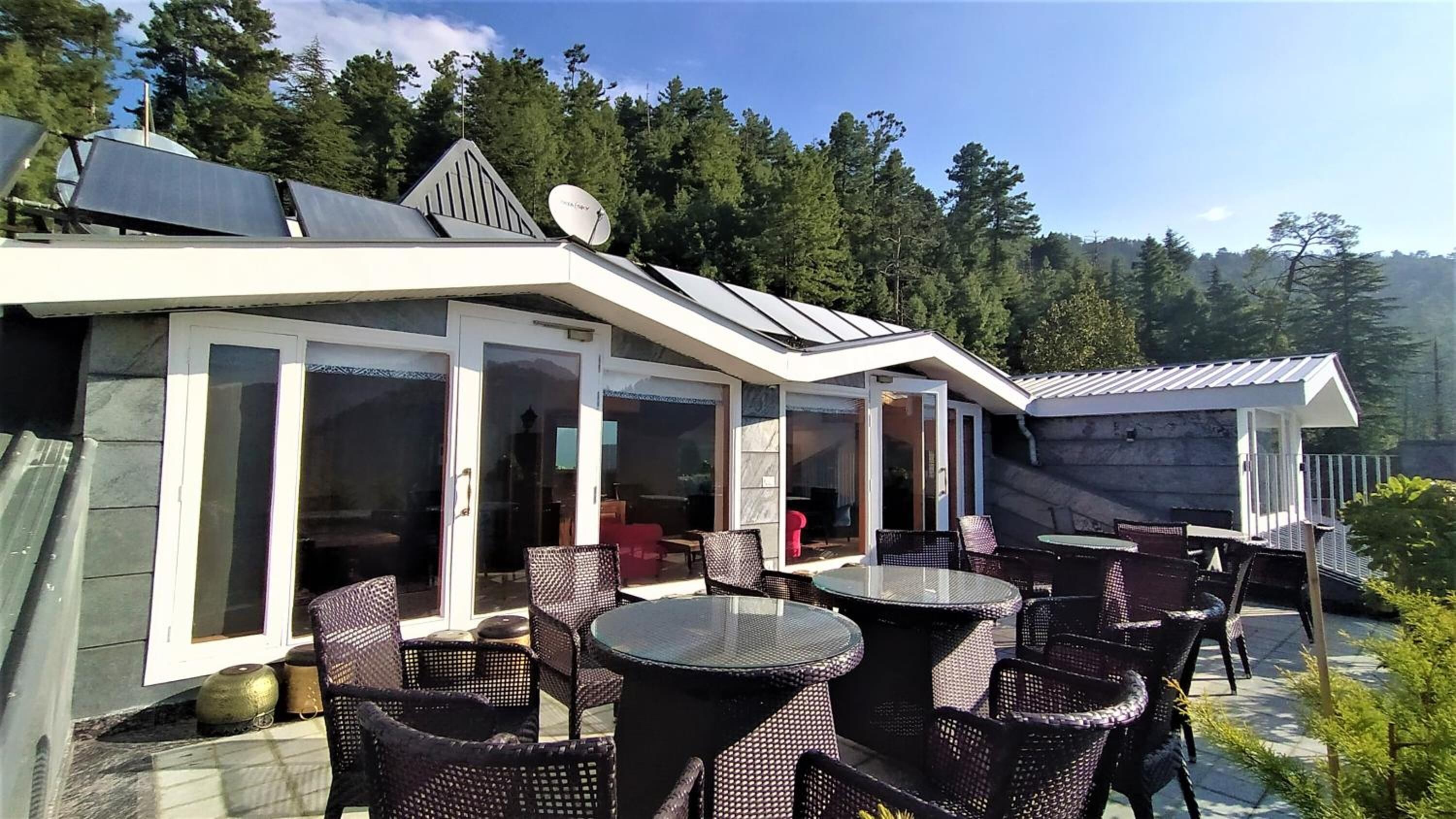 A modern outdoor patio with glass doors, wicker furniture, and solar panels.
