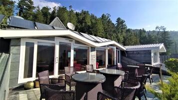 Un patio moderno al aire libre con puertas de vidrio, mobiliario de mimbre y paneles solares.