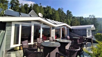 Un patio moderno al aire libre con puertas de vidrio, mobiliario de mimbre y paneles solares.