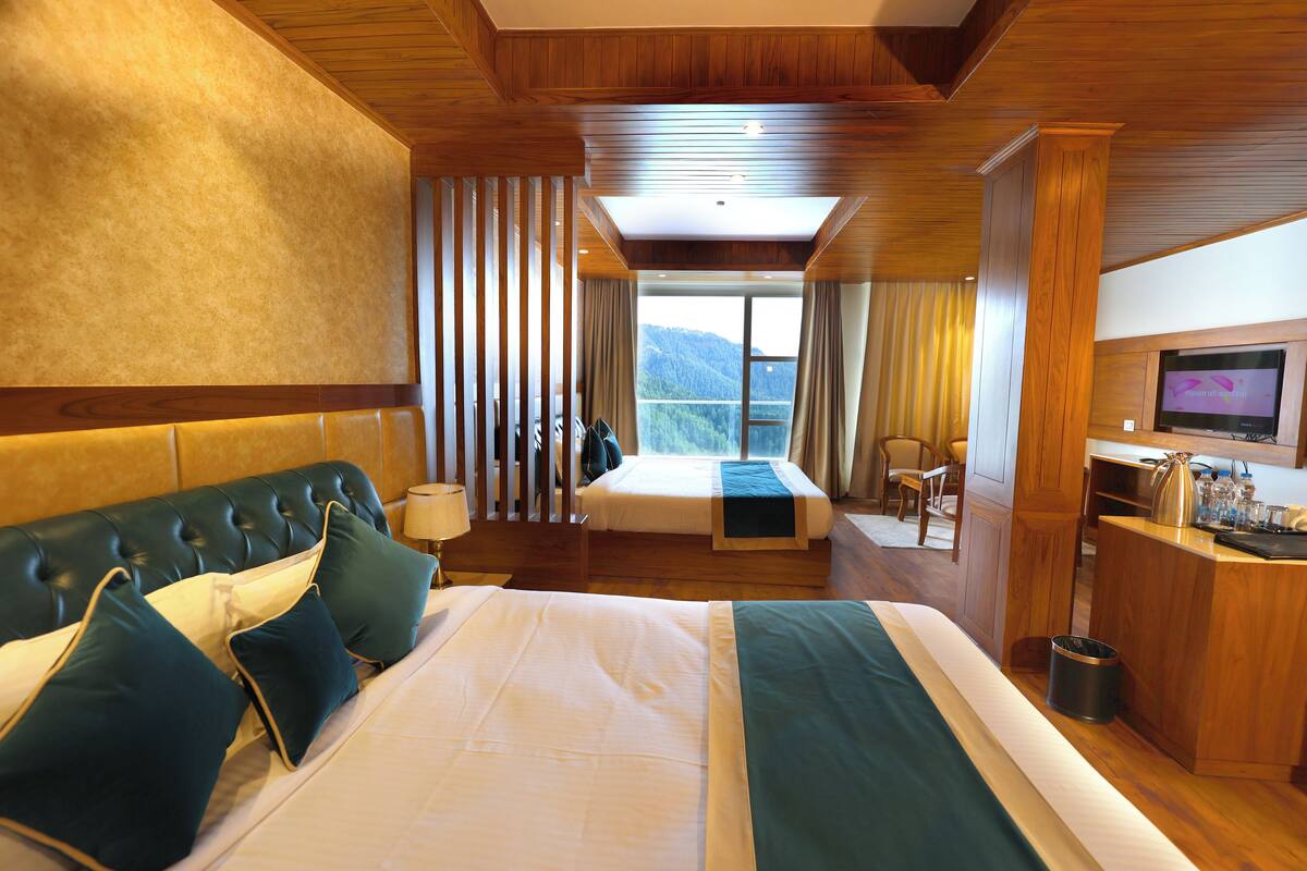 Habitación de hotel con una cama grande, un escritorio, televisión y vistas a la montaña.
