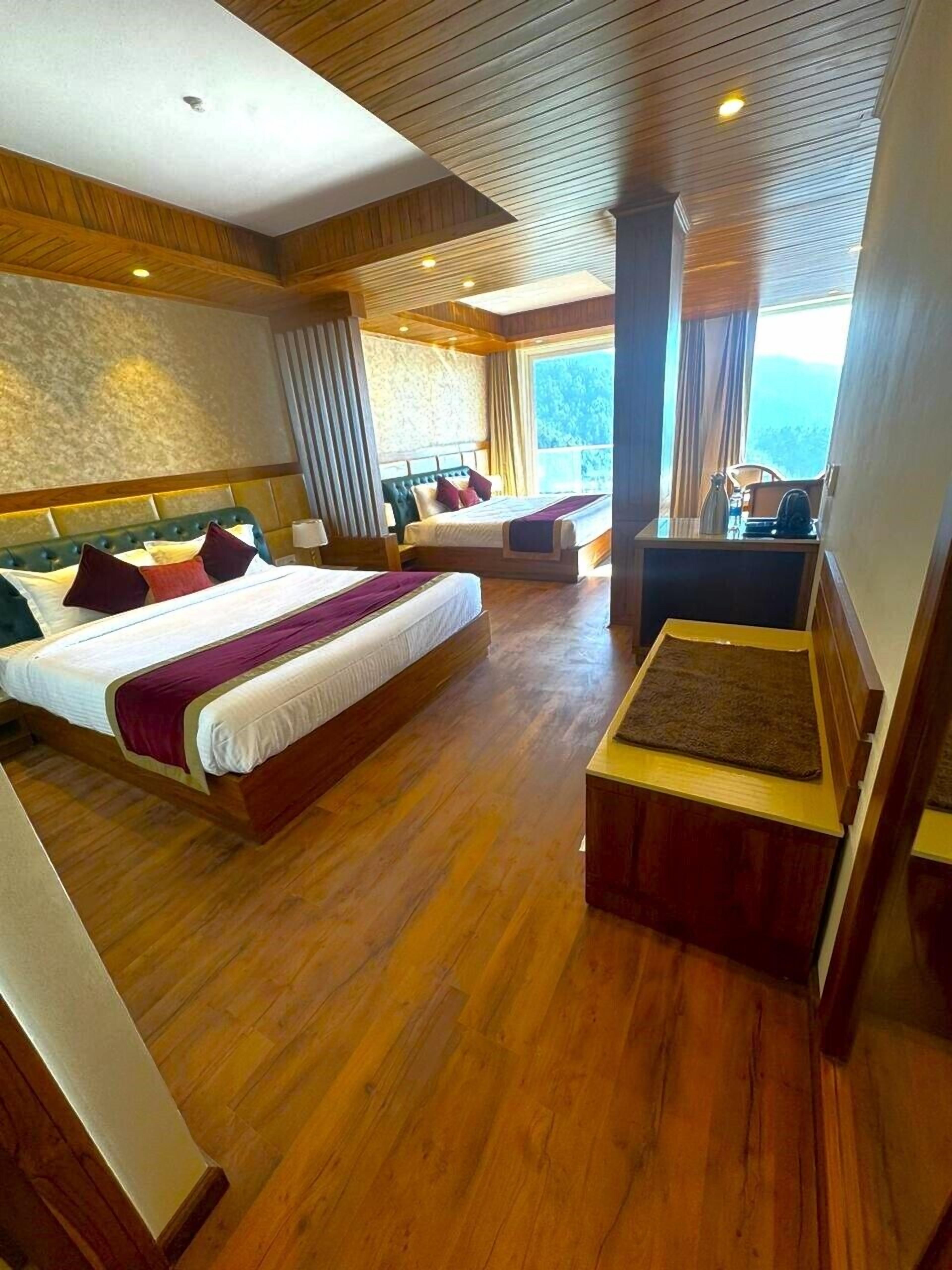 Une chambre d’hôtel avec deux lits, un plancher en bois, une grande fenêtre avec des rideaux et une vue sur l’extérieur.
