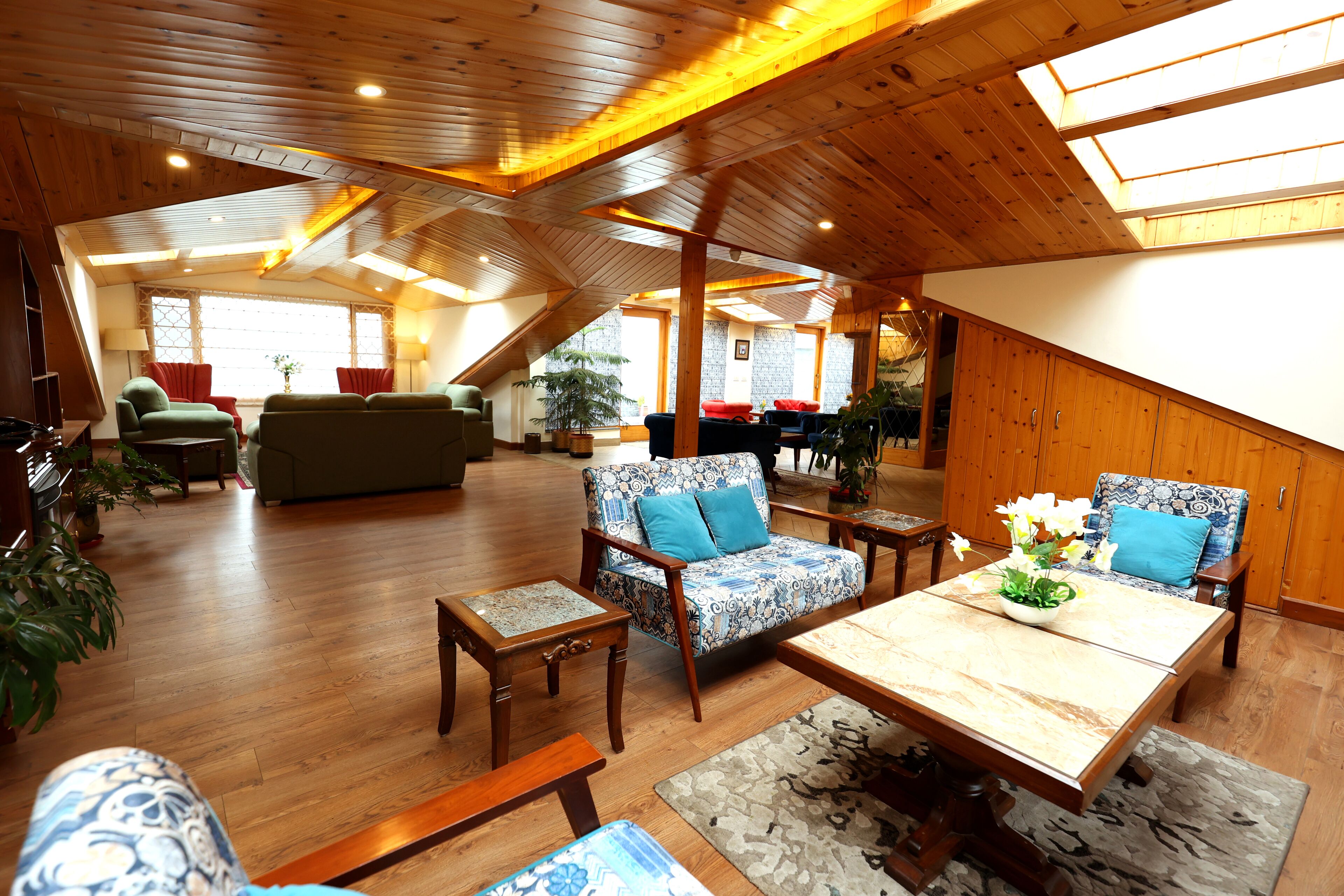 A spacious loft-style living area with high ceilings, wooden beams, and skylights.