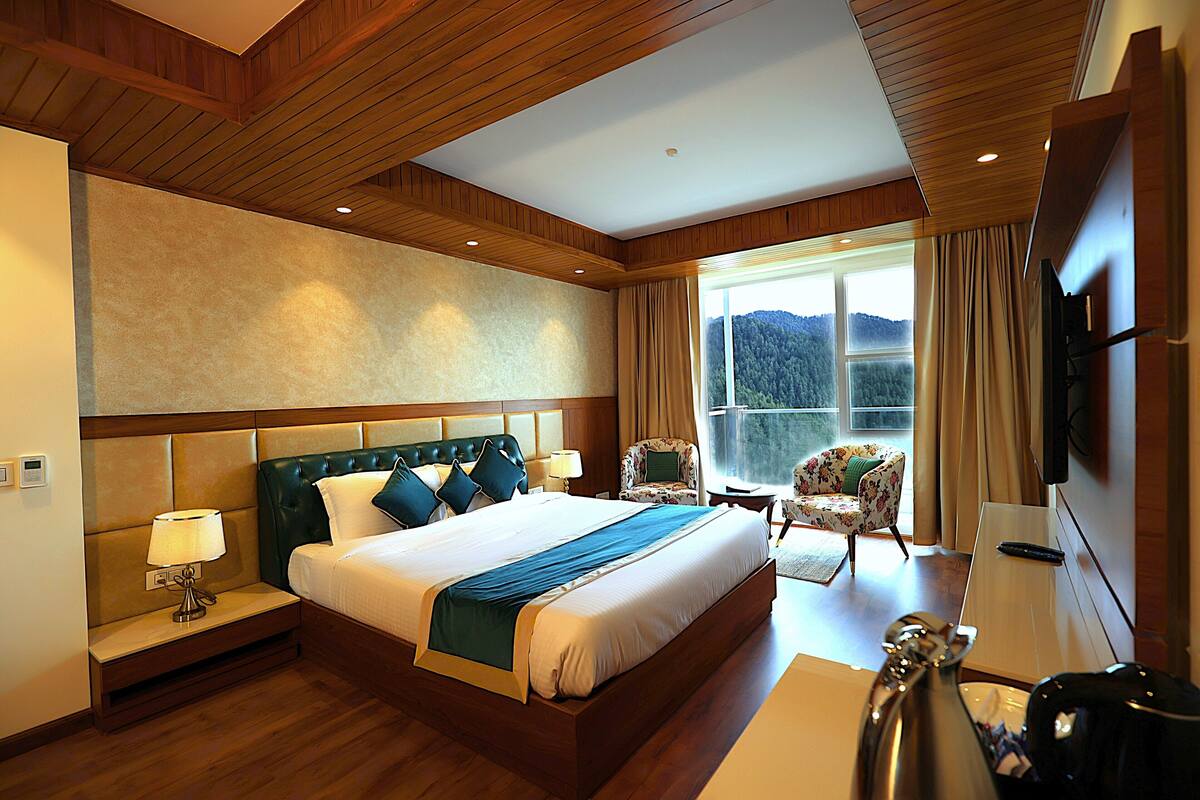 Habitación de hotel con una cama grande, un escritorio, una silla, un televisor y una ventana con vistas al exterior.