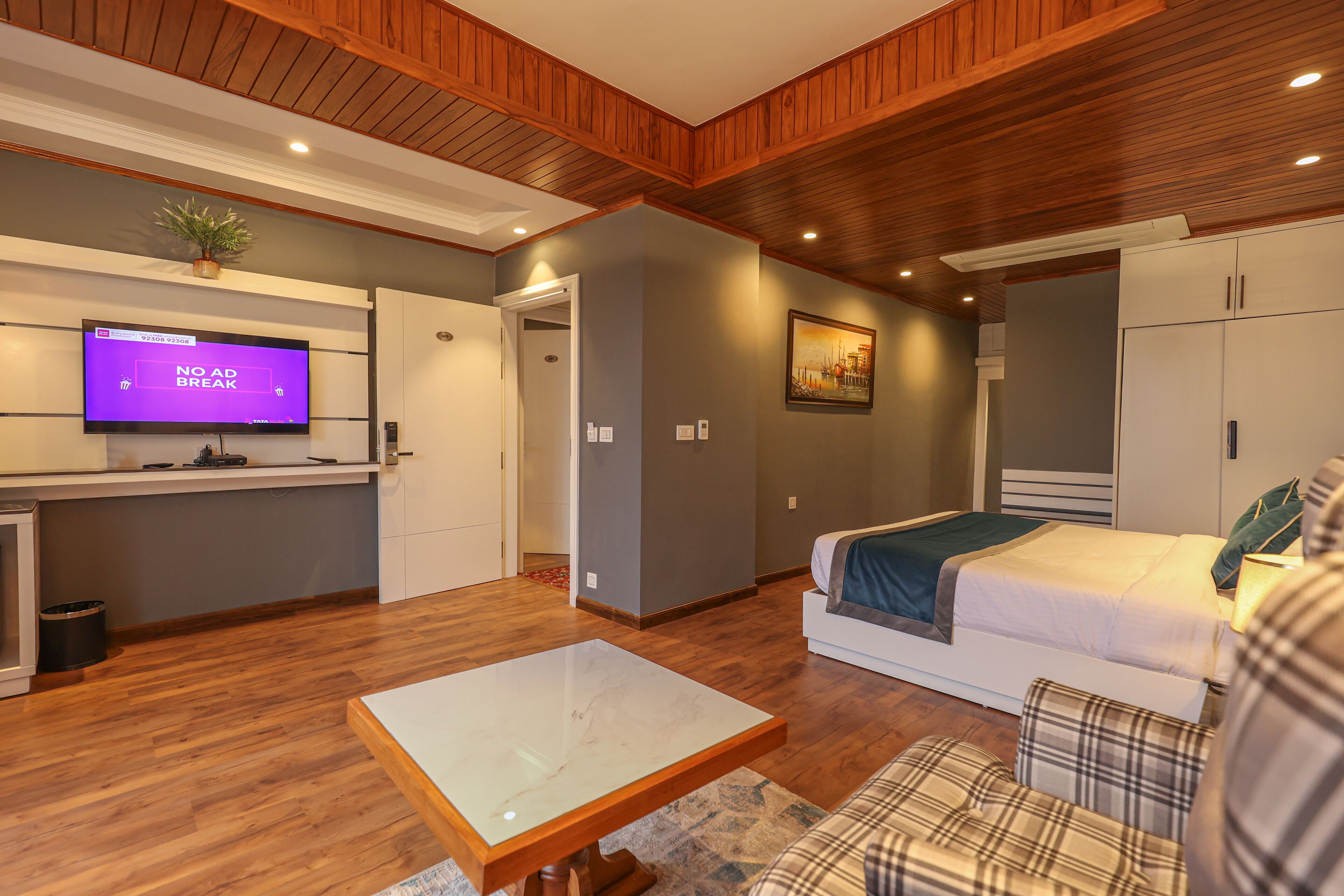 Une chambre moderne équipée d’un lit, d’un canapé, d’une télévision et d’un plancher en bois.