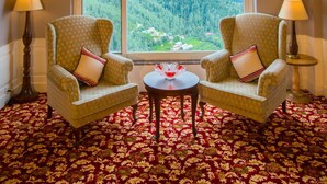 A room with two armchairs facing a large window with a mountain view, a small table, and wooden ceiling panels. - The Retreat Mashobra, Shimla (Shimla)