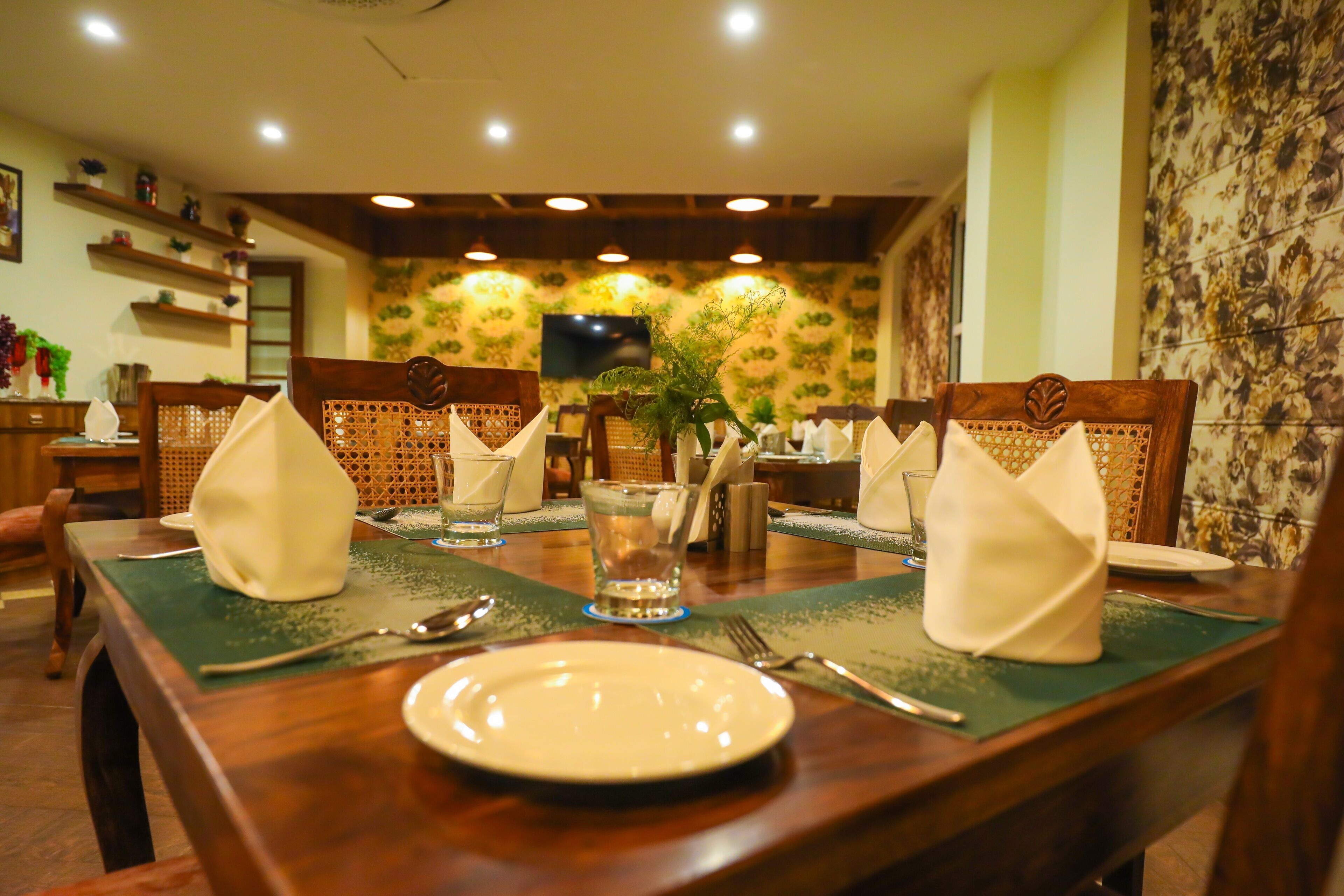Comedor con mesas y sillas de madera, y camino de mesa verde.