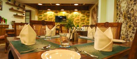 Comedor con mesas y sillas de madera, y camino de mesa verde.