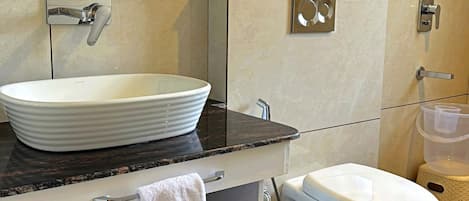Une salle de bain moderne avec un grand lavabo blanc, des toilettes et un miroir au-dessus du lavabo.
