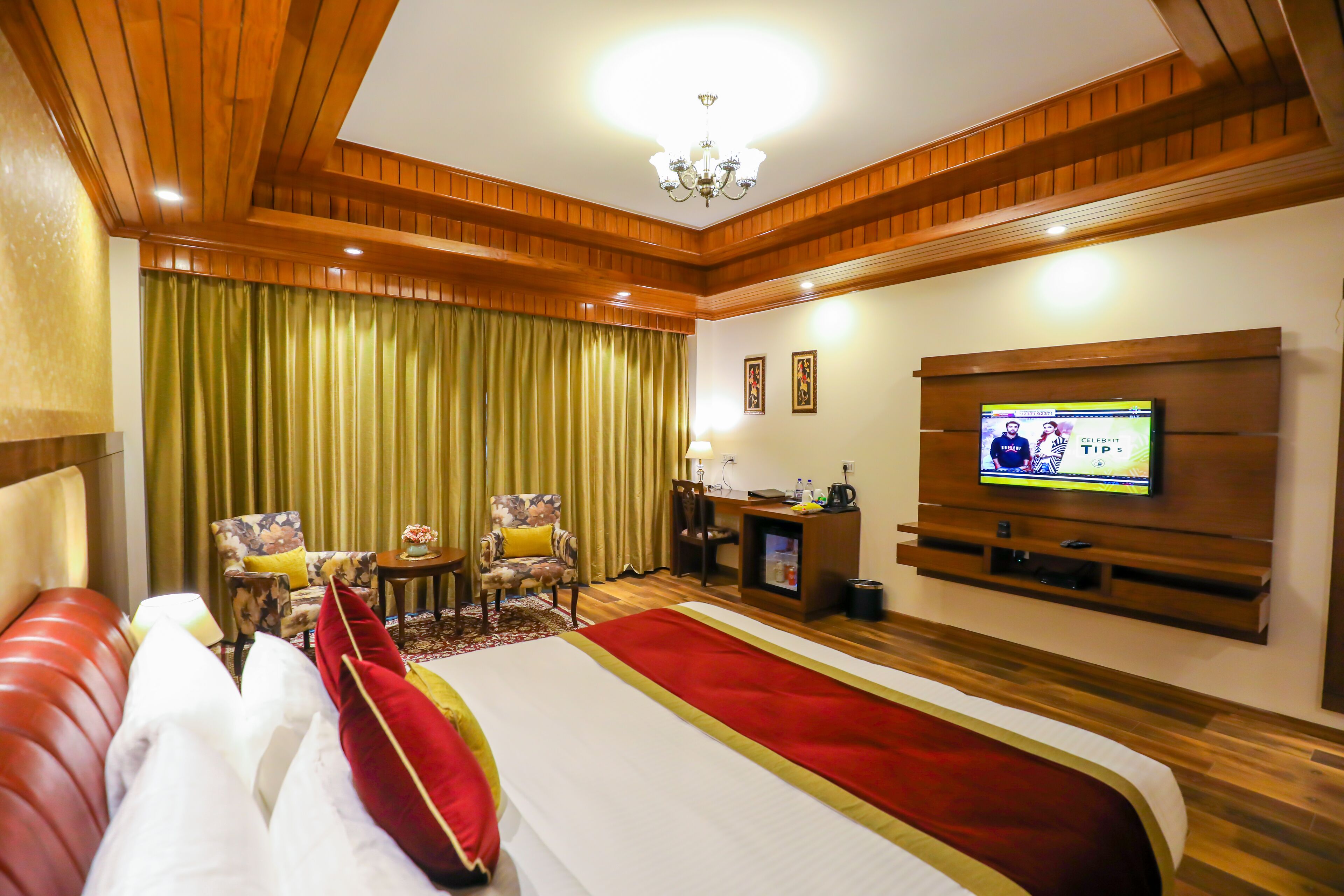 A hotel room with a large bed, a TV, a desk, and a chair.