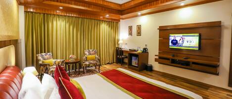 A hotel room with a large bed, a TV, a desk, and a chair.