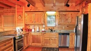 Una cocina tipo cabaña de madera con estufa, refrigerador y armarios de madera.
