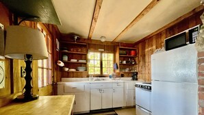 Una cucina con pareti in legno, un frigorifero bianco, un fornello e un lavello.