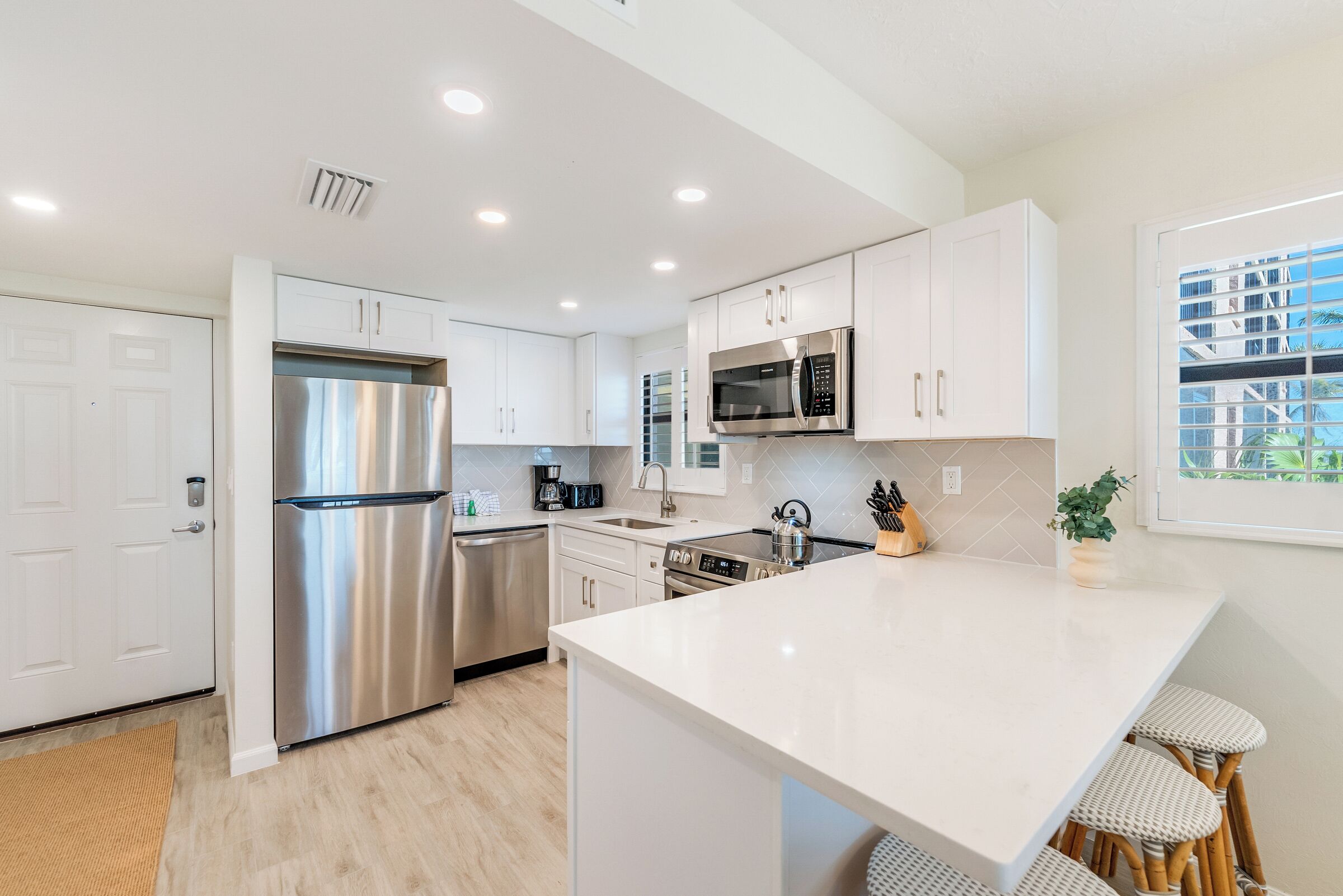 A modern kitchen with white cabinets, stainless steel appliances, and a large island with bar stools.