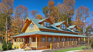 A large wooden lodge with a prominent front porch and multiple windows. - Bear-riffic View | Hot Tub, Games & Scenic Decks (Sevierville)