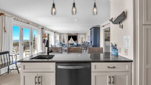 A spacious kitchen with a large island, white cabinetry, and pendant lighting. - Jonah's Whale: Large Oceanfront Home, Ocean and Waterway Views (Caswell Beach)