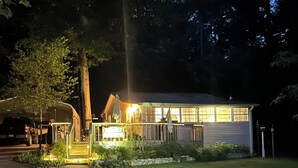 A two-story house with a front porch, a garage, and a well-lit driveway. - Lakehouse, Sleeps 6, Private Dock, Infinity Beach Pit, 2 Kayaks! (Hawkins)